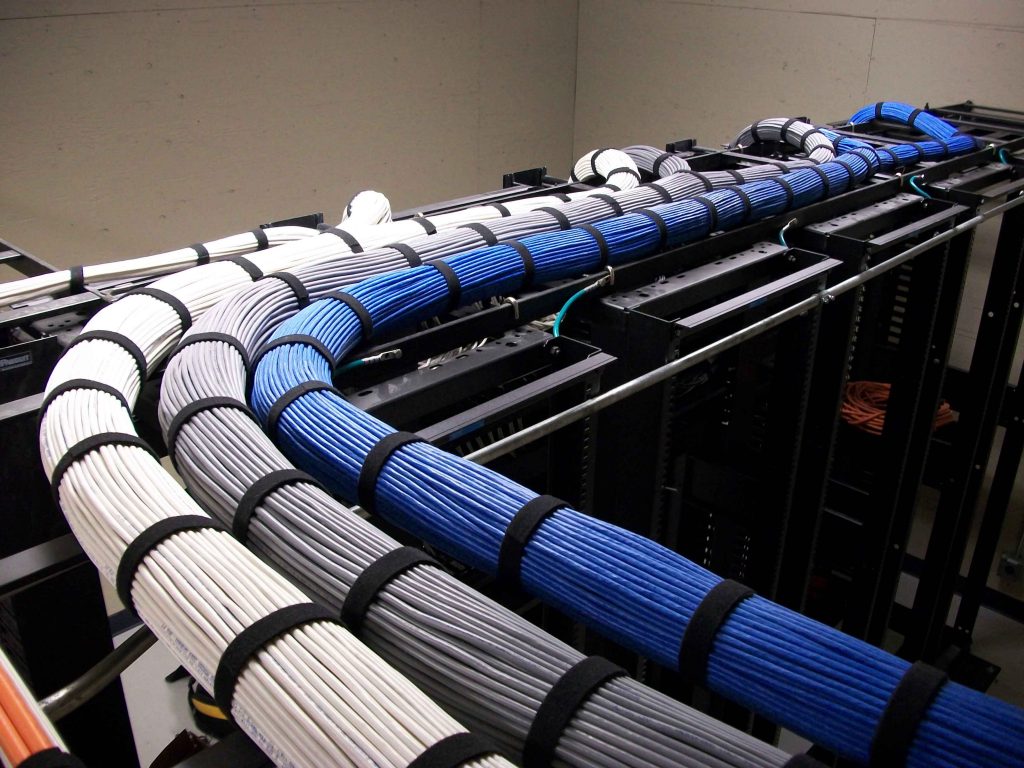 Bundled and dressed cat6 cables running on cable trays on top of server racks in server room.