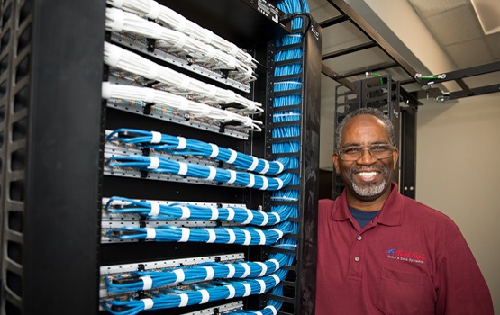 Double Eagle certified cabling technician proudly showing terminated server rack back side cable dressing.