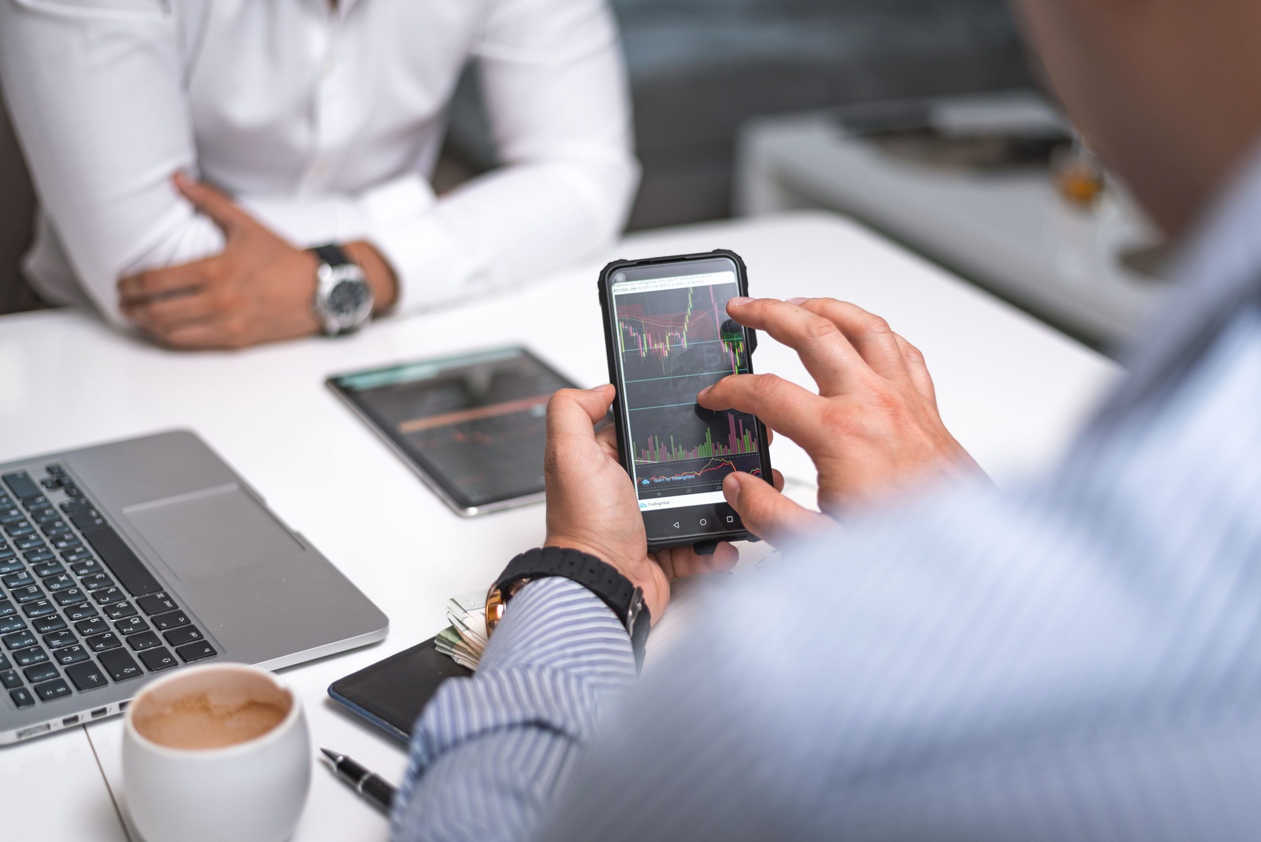 Business professional using a smartphone beside office computer screens