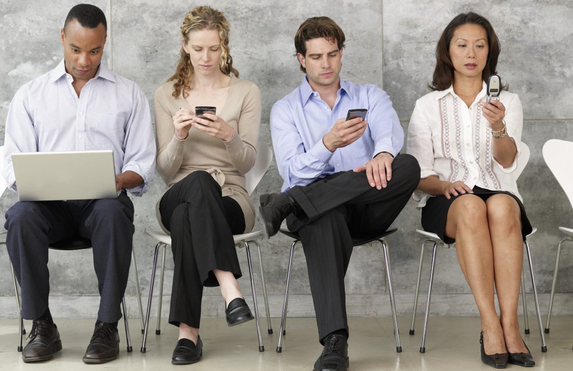 Four people in waiting room using wi-fi devices.